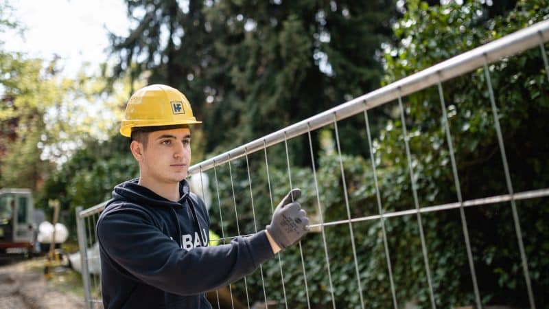 Arbeiter von Held & Francke der an einem Bauzaun steht
